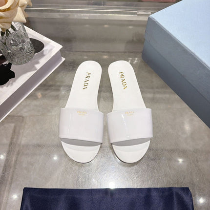 PRADA 26S LOGO EMBOSSED SLIDE SANDALS IN WHITE PATENT CALFSKIN