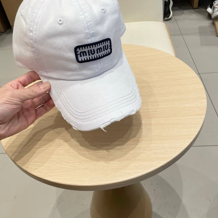 MIUMIU DISTRESSED FABRIC BASEBALL CAP IN WHITE WITH EMBROIDERED LOGO