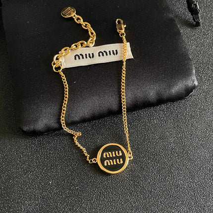 MIUMIU 26S LOGO ROUND BRACELET IN BLACK ENAMEL AND GOLD TONE METAL 631809