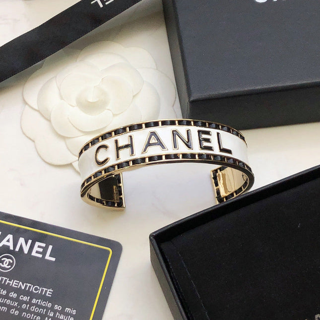 CHANEL 26S CHANEL LOGO ENAMEL CUFF BRACELET WITH BLACK TRIM IN GOLD METAL 630835
